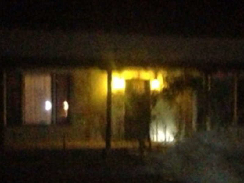 Blurry nighttime image of a building exterior with dimly lit windows and a misty, ethereal glow, creating an eerie atmosphere.