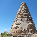 Stone pyramid-shaped monument against a clear blue sky, known as the Schieffelin Monument in Tombstone, Arizona