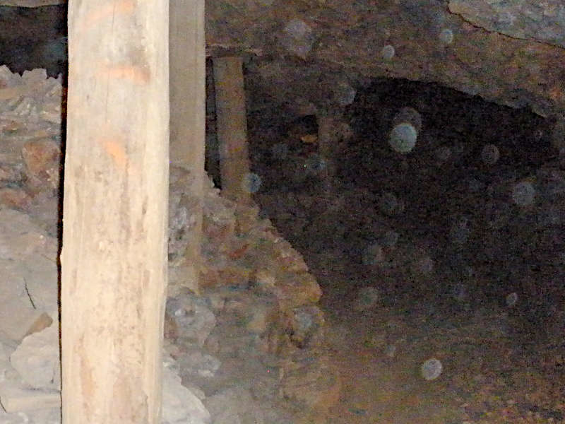 Dark interior of a stone structure with a wooden beam visible on the left, an old mine entrance.