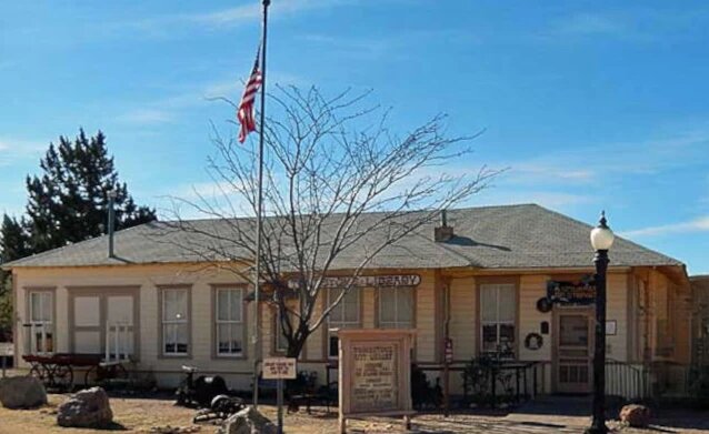 Historic Tombstone railroad depot, now serving as public library, with American flag and desert landscaping.