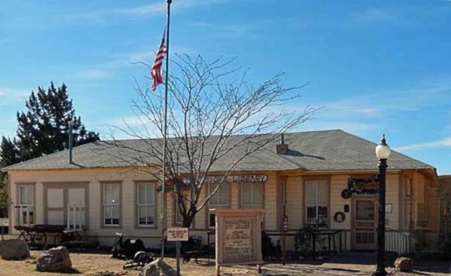 Historic Tombstone railroad depot, now serving as public library, with American flag and desert landscaping.